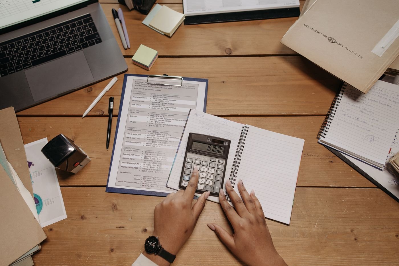 Calcul du montant de la CFE et de la taxe d'habitation d'une location saisonnière sur un bureau avec calculatrice et documents