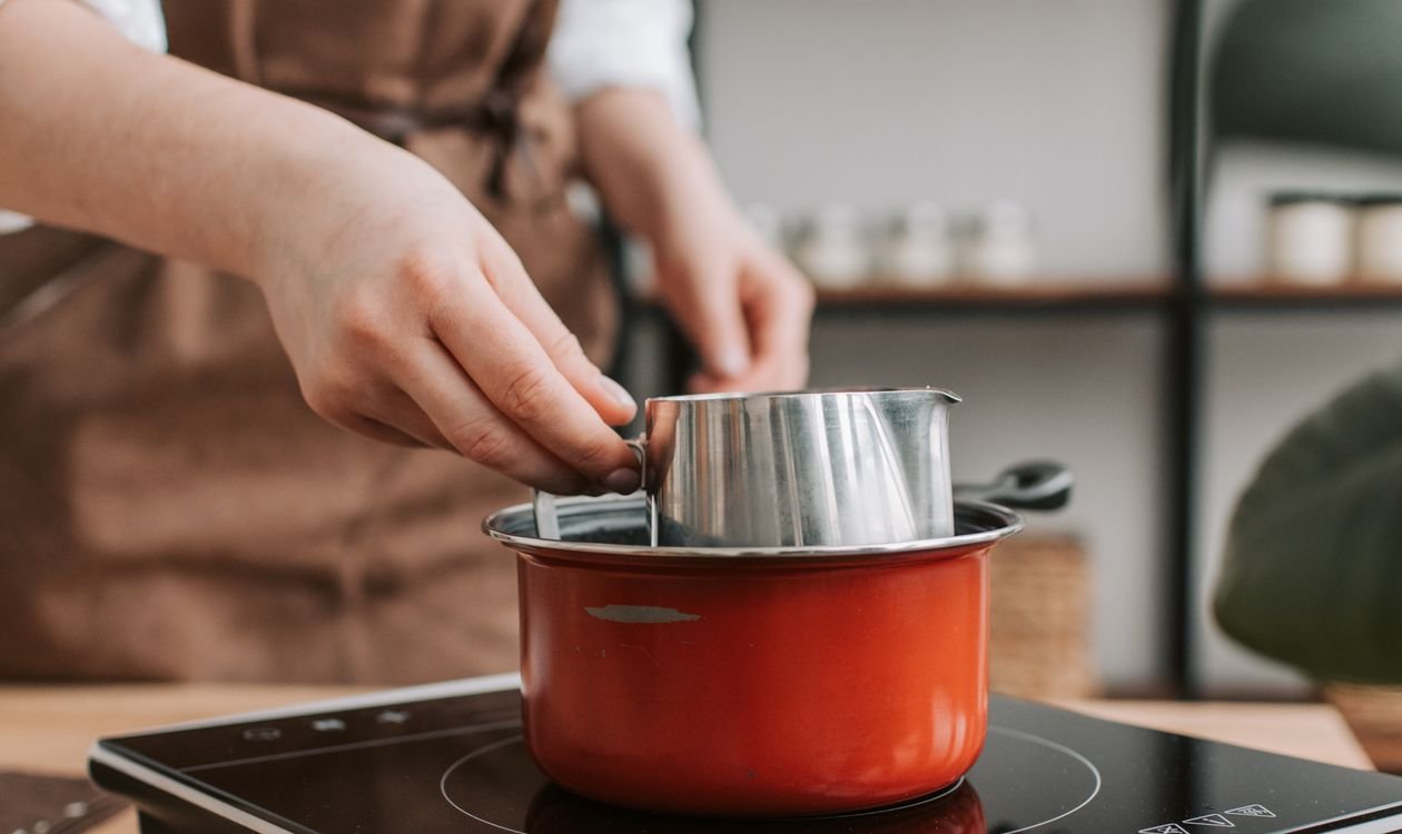 Casserole posée sur une plaque à induction dont le bandeau tactile affiche ses symboles de commande