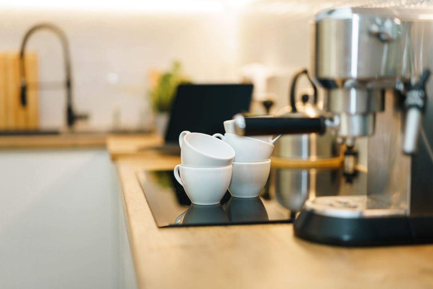 Machine à expresso et tasses blanches installées sur le comptoir d'une cuisine équipée